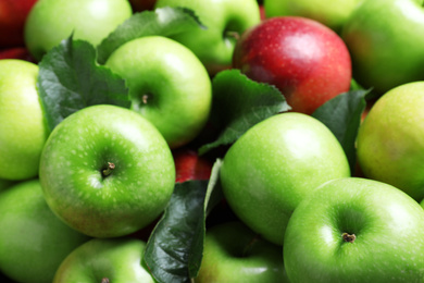 Photo of Pile of tasty ripe apples with leaves as background, closeup
