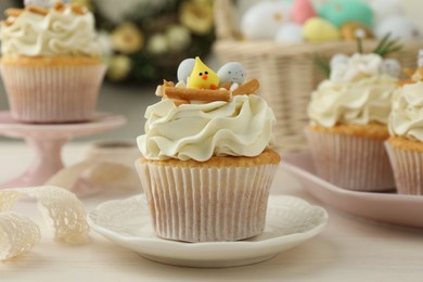 Tasty Easter cupcakes with vanilla cream on light wooden table