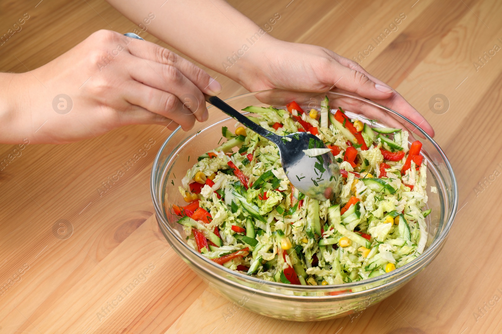 Photo of Woman making tasty salad with Chinese cabbage at wooden table, closeup