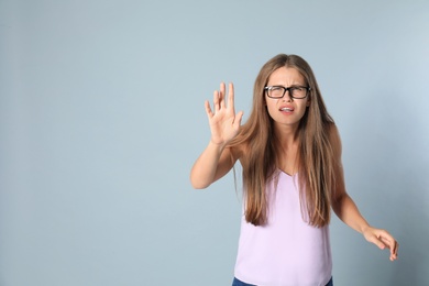 Photo of Young woman with vision problems wearing glasses on grey background, space for text