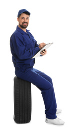 Photo of Professional auto mechanic with tire and clipboard on white background