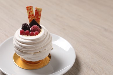 Photo of Delicious meringue dessert with berries on wooden table, closeup. Space for text