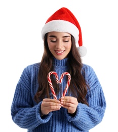 Photo of Beautiful woman in Santa Claus hat making heart with candy canes on white background
