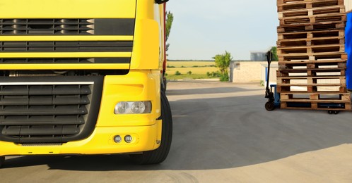 Modern manual forklift with wooden pallets near truck outdoors on sunny day