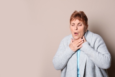 Photo of Elderly woman coughing against color background. Space for text