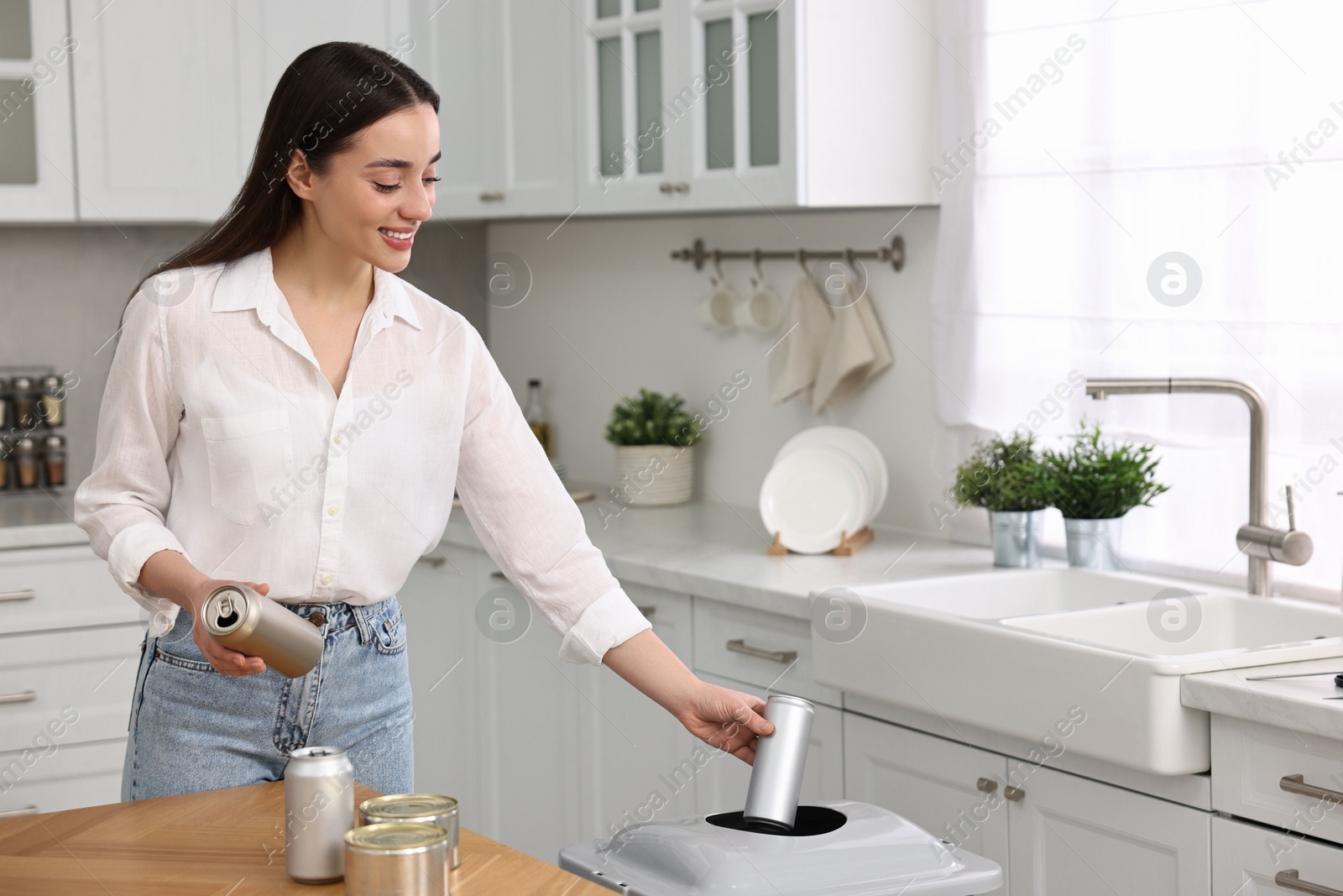 Photo of Smiling woman separating garbage in kitchen. Space for text