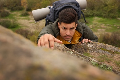 Hiker with backpack climbing up mountain on autumn day