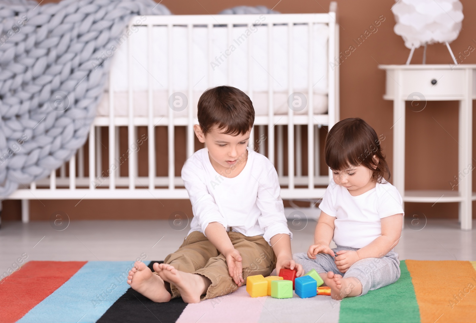 Photo of Cute little boy playing with his baby sister at home