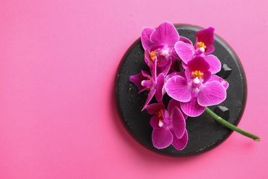 Photo of Spa stone and beautiful orchid flowers on pink background, top view. Space for text