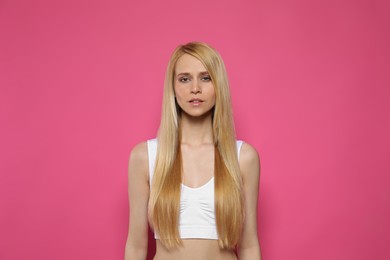 Photo of Beautiful young woman with long straight hair on pink background