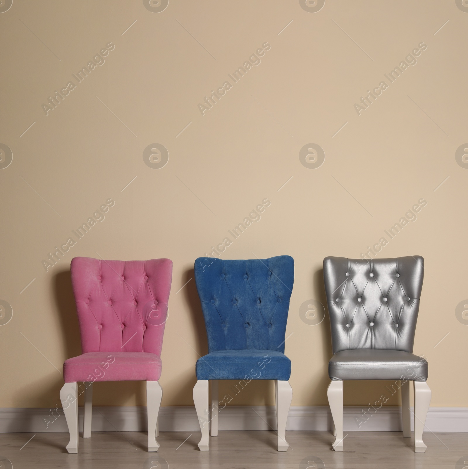 Photo of Different elegant stylish chairs near beige wall