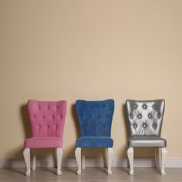 Photo of Different elegant stylish chairs near beige wall