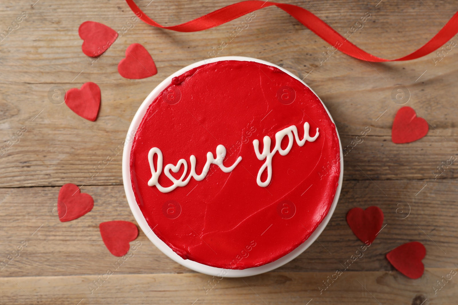 Photo of Bento cake with text Love You and paper hearts on wooden table, top view. St. Valentine's day surprise