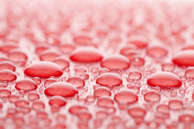 Photo of Water drops on red background, closeup view