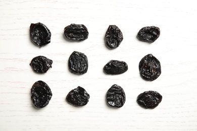 Photo of Flat lay of dried plums on wooden background. Healthy fruit