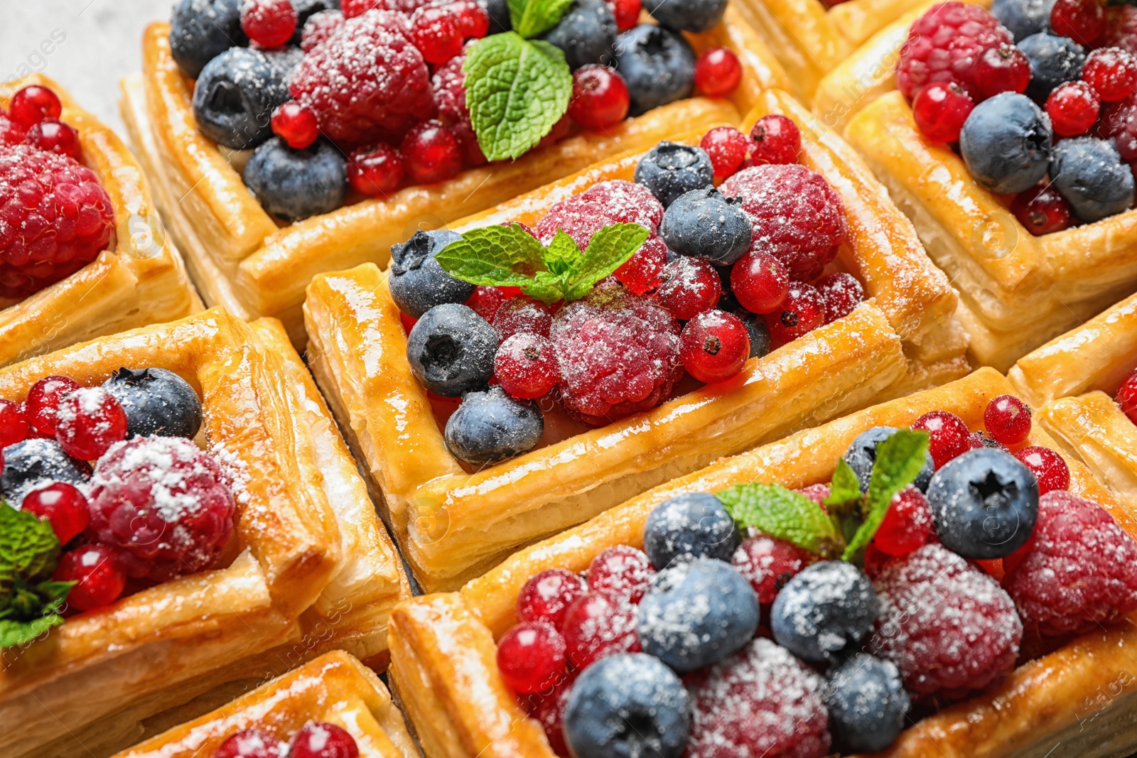 Photo of Fresh delicious puff pastry with sweet berries as background, closeup