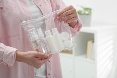 Photo of Woman holding plastic bag of cosmetic travel kit indoors, closeup and space for text. Bath accessories