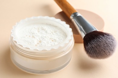 Photo of Makeup brush with rice loose face powder on beige background, closeup