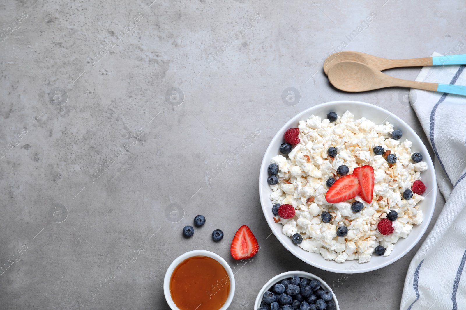 Photo of Delicious cottage cheese with fresh berries served on light grey table, flat lay. Space for text