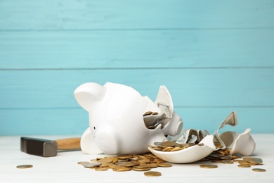 Photo of Broken piggy bank with money and hammer on table