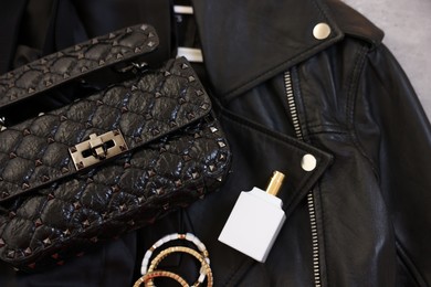 Bracelets, bottle of perfume, bag and black leather jacket , flat lay