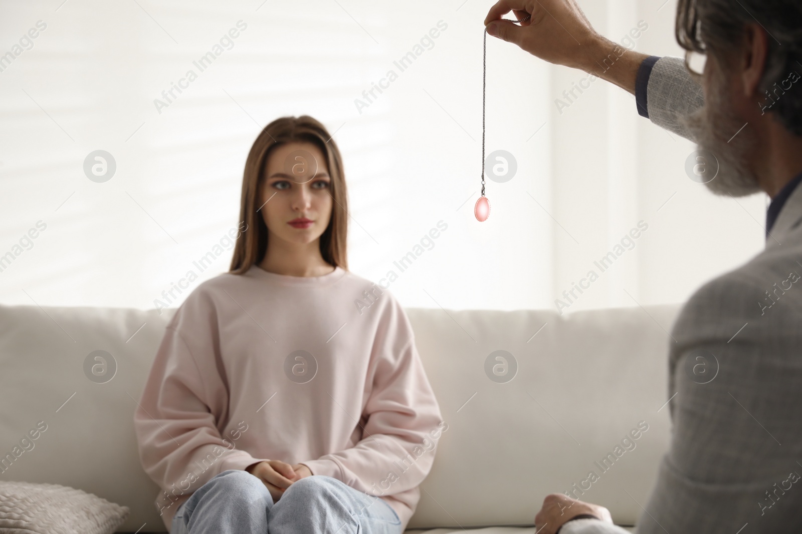 Photo of Psychotherapist using pendulum during hypnotherapy   session in office