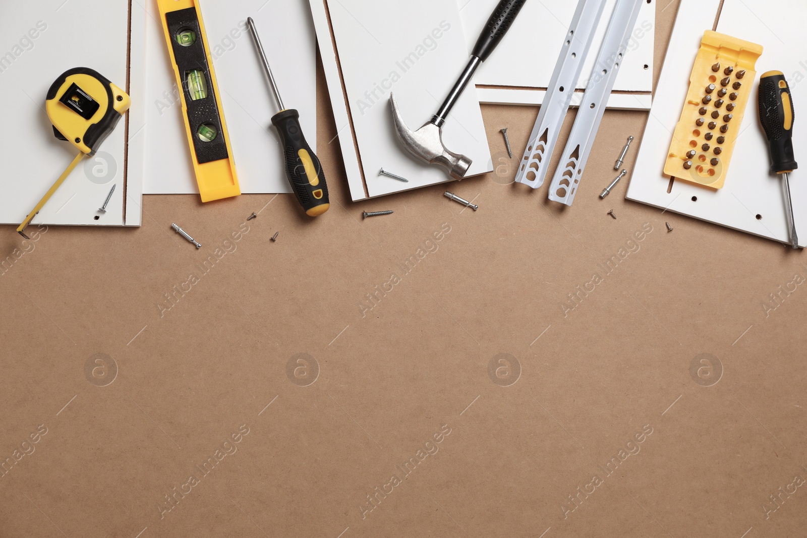 Photo of Flat lay composition with furniture assembly parts and tools on brown background. Space for text