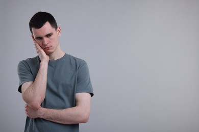 Portrait of sad man on grey background, space for text