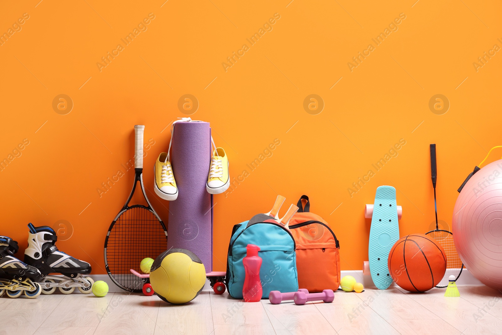 Photo of Many different sports equipment near orange wall indoors