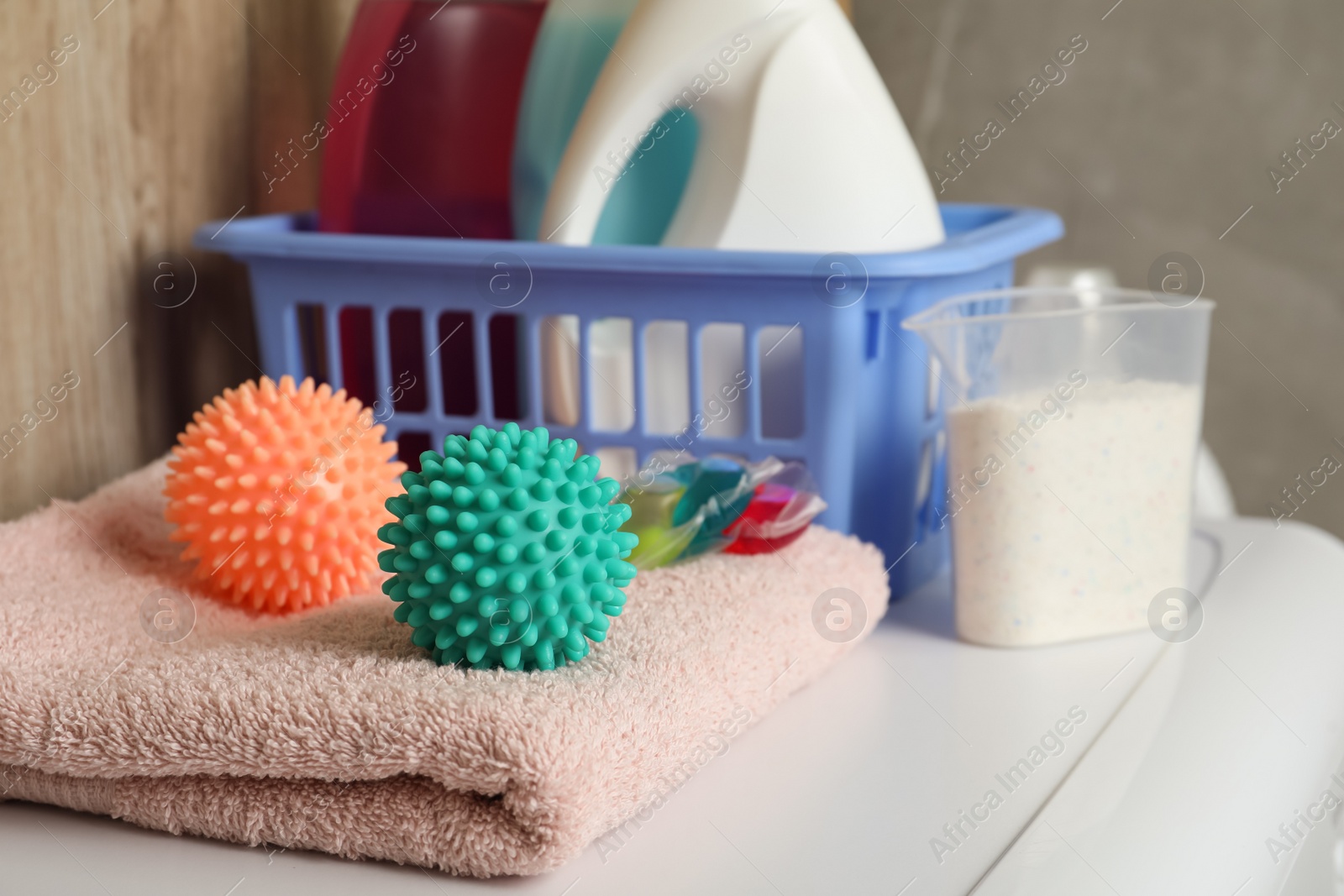 Photo of Dryer balls, detergents and clean towel on washing machine