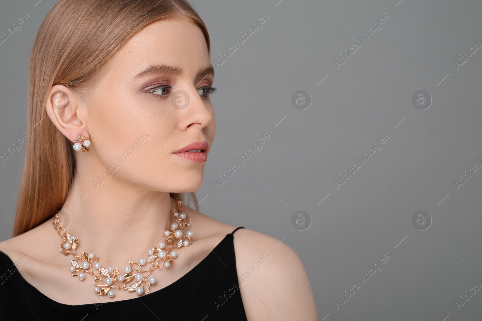 Photo of Beautiful young woman with elegant jewelry on gray background, space for text