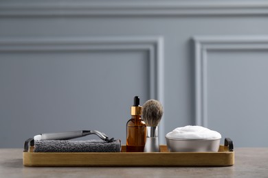 Set of men's shaving tools in wooden tray on grey table