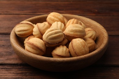 Delicious nut shaped cookies with boiled condensed milk in bowl on wooden table, closeup