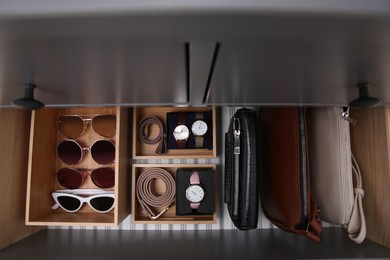 Open drawer with different stylish accessories indoors, top view. Storage and organizing