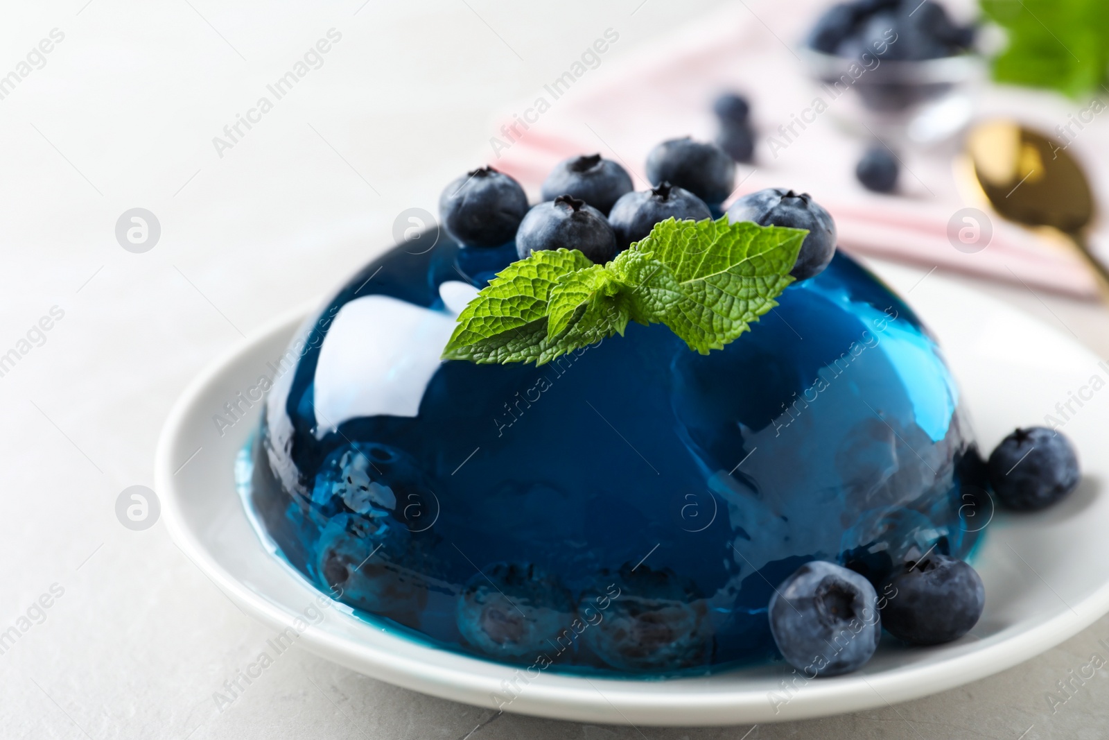 Photo of Delicious jelly with blueberries and mint on grey table
