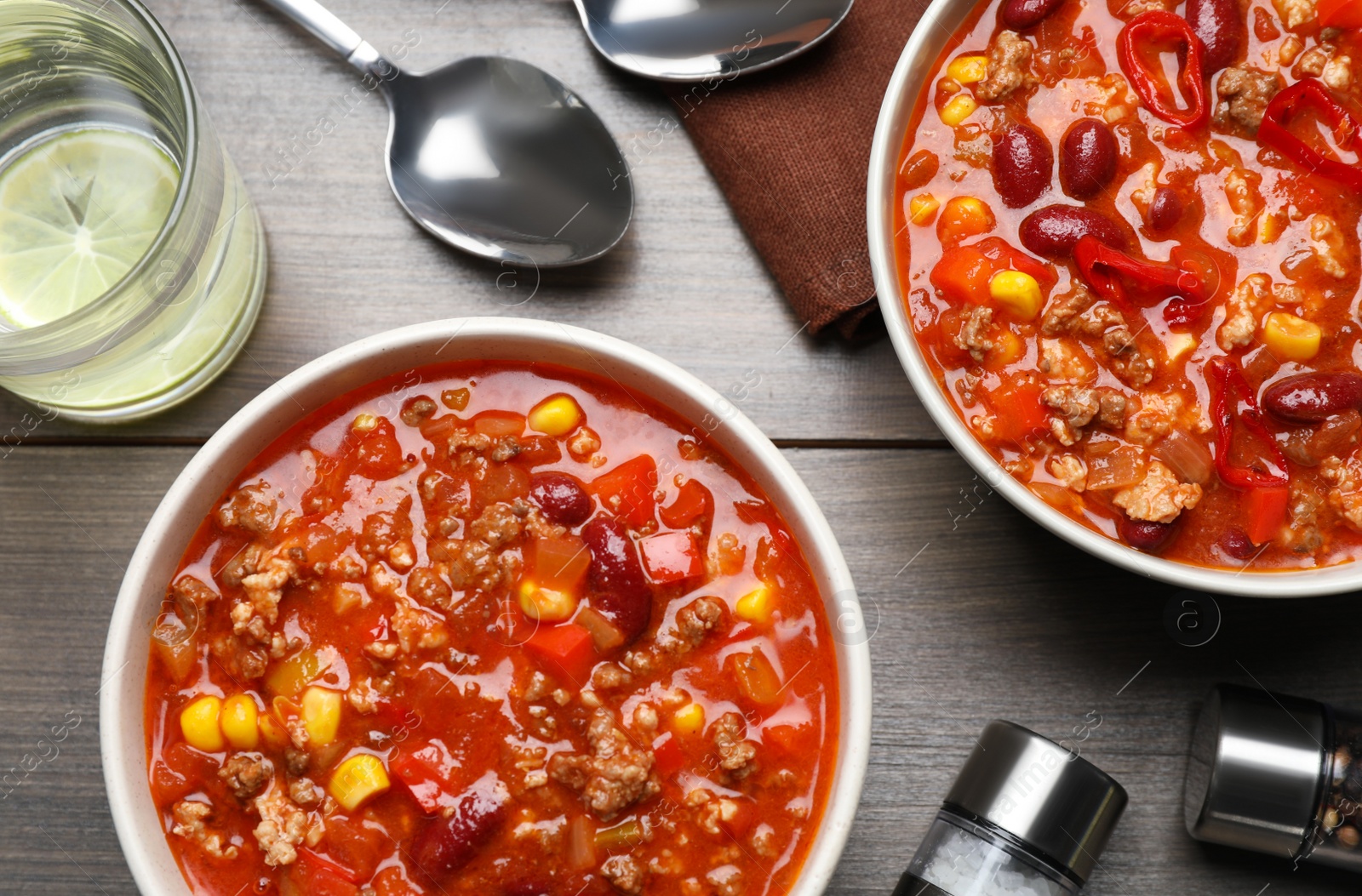 Photo of Tasty chili con carne served on wooden table, flat lay