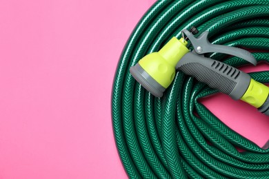 Watering hose with sprinkler on pink background, top view. Space for text