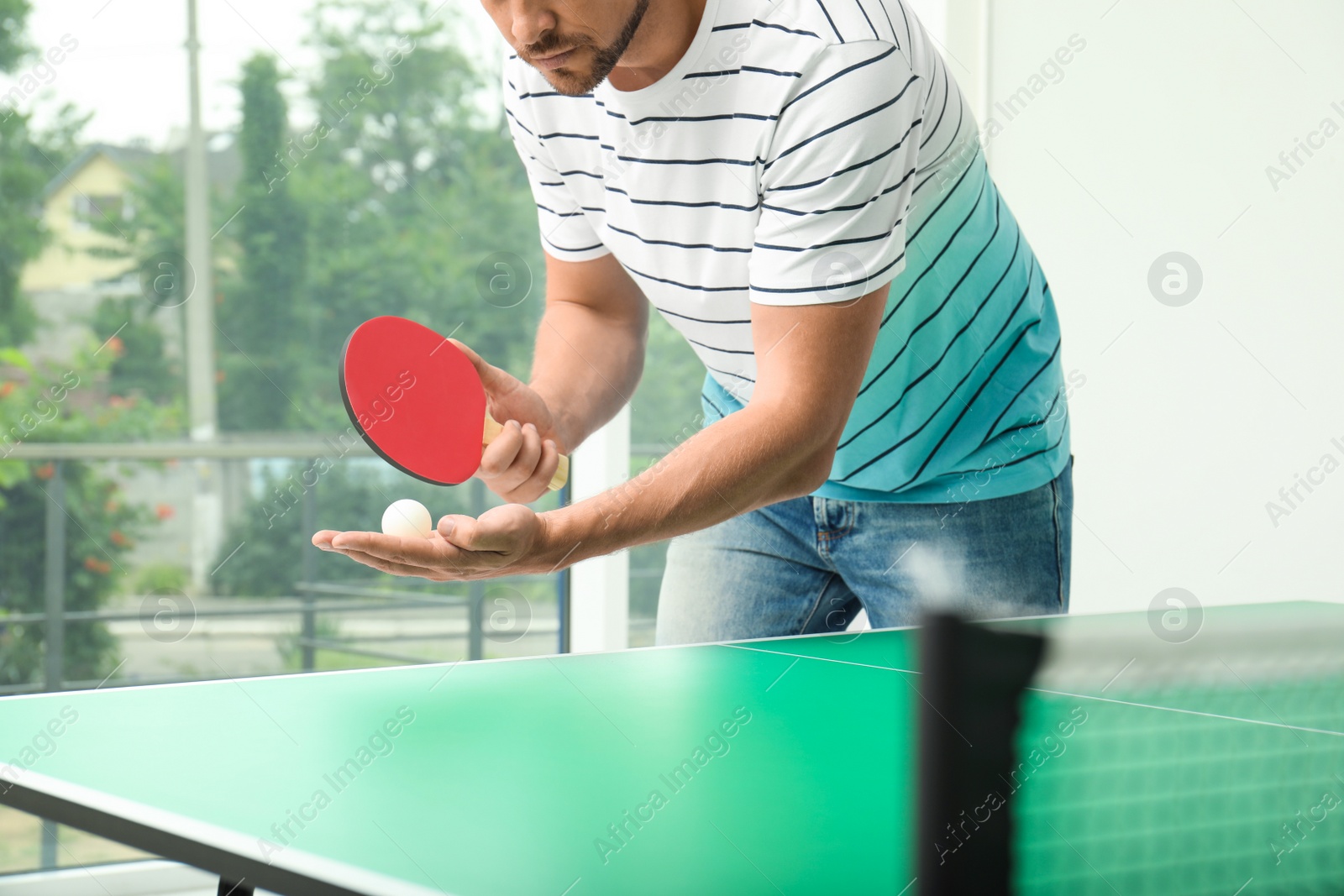 Photo of Man playing ping pong indoors, closeup view