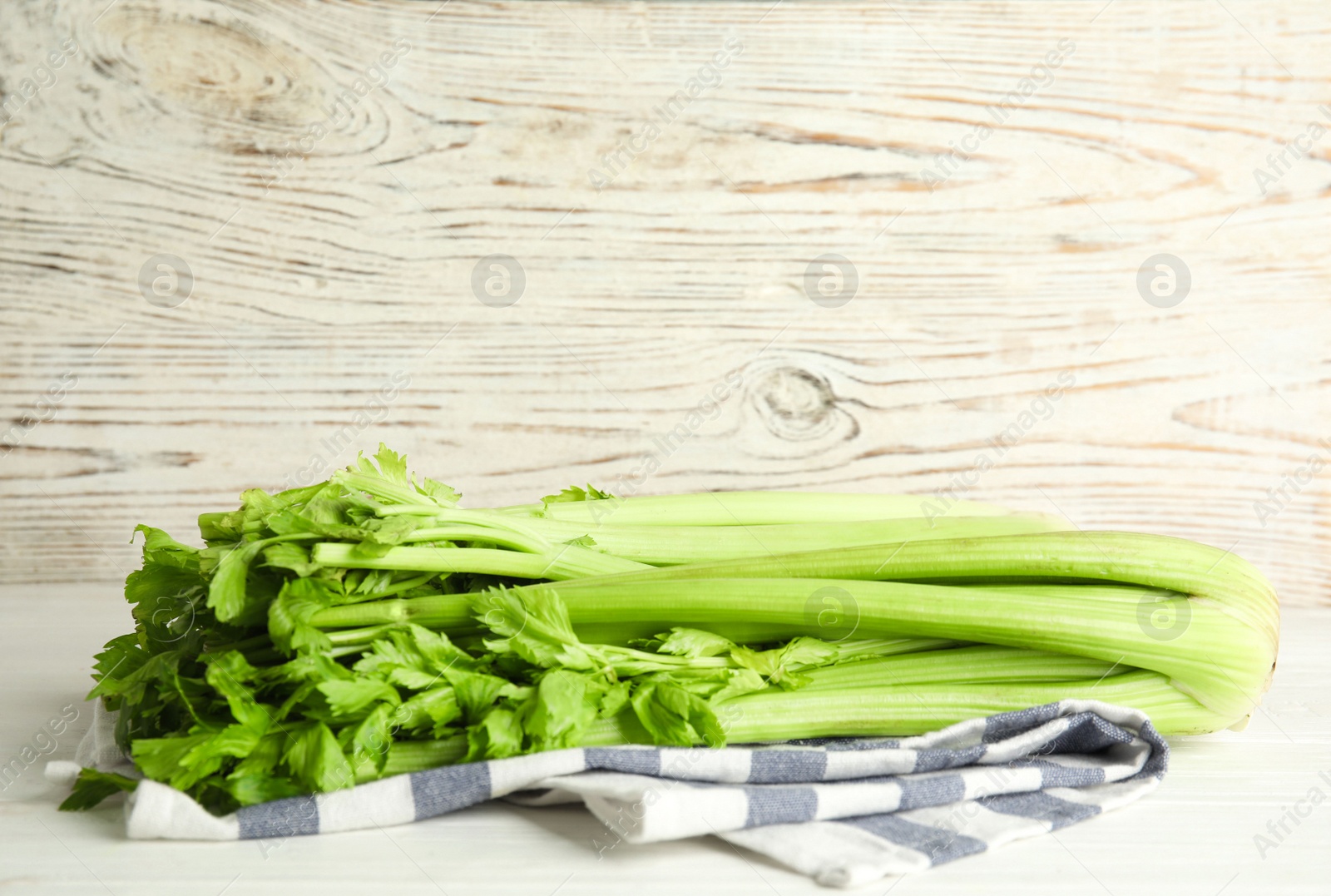 Photo of Fresh ripe green celery on white wooden table. Space for text