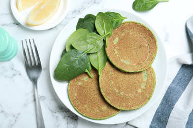 Tasty spinach pancakes served on white marble marble table, flat lay