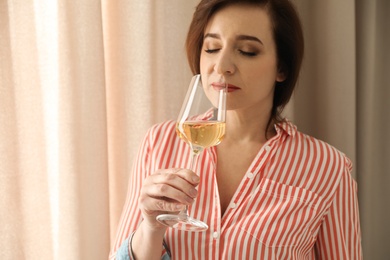 Photo of Woman with glass of wine indoors. Space for text