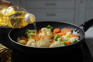 Woman pouring cooking oil from bottle into frying pan with vegetables, closeup