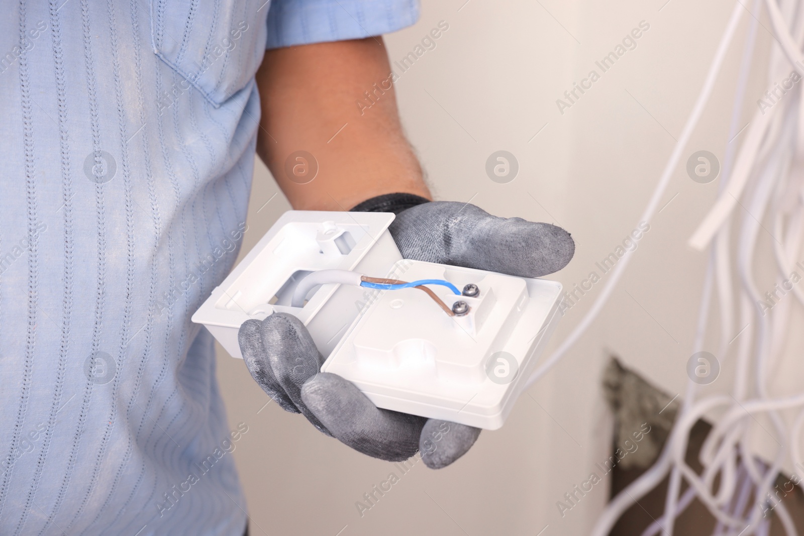 Photo of Electrician with remote meter indoors, closeup. Installation of electrical wiring