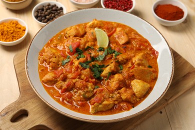 Photo of Delicious chicken curry and spices on wooden table