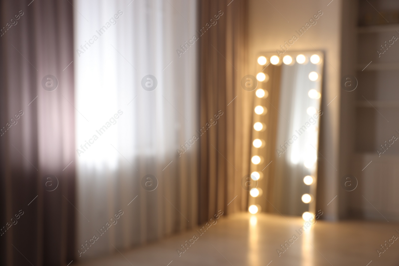 Photo of Modern mirror with light bulbs in makeup room, blurred view