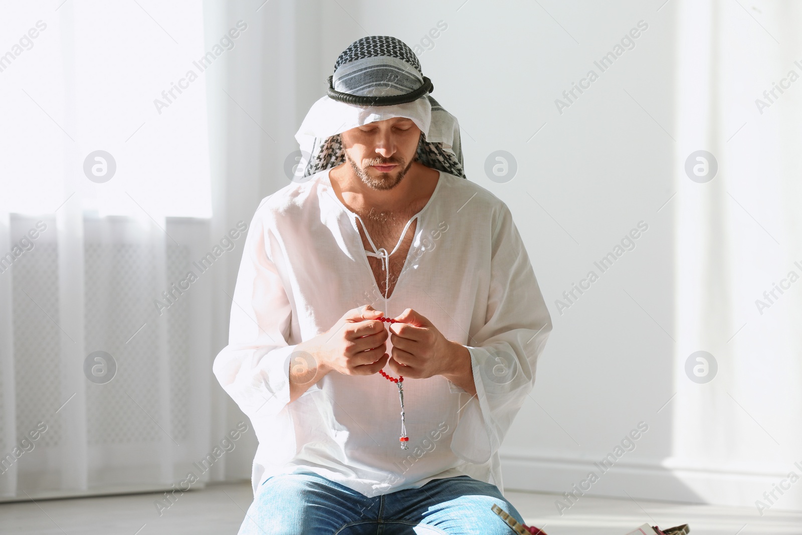 Photo of Muslim man in traditional clothes praying indoors