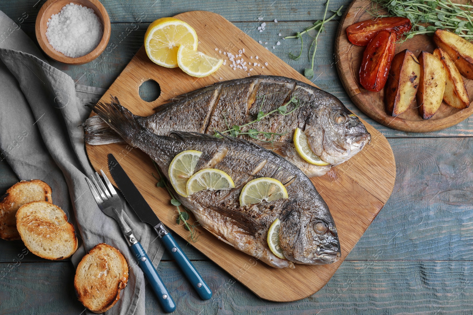 Photo of Delicious baked fish served on wooden rustic table, flat lay. Seafood