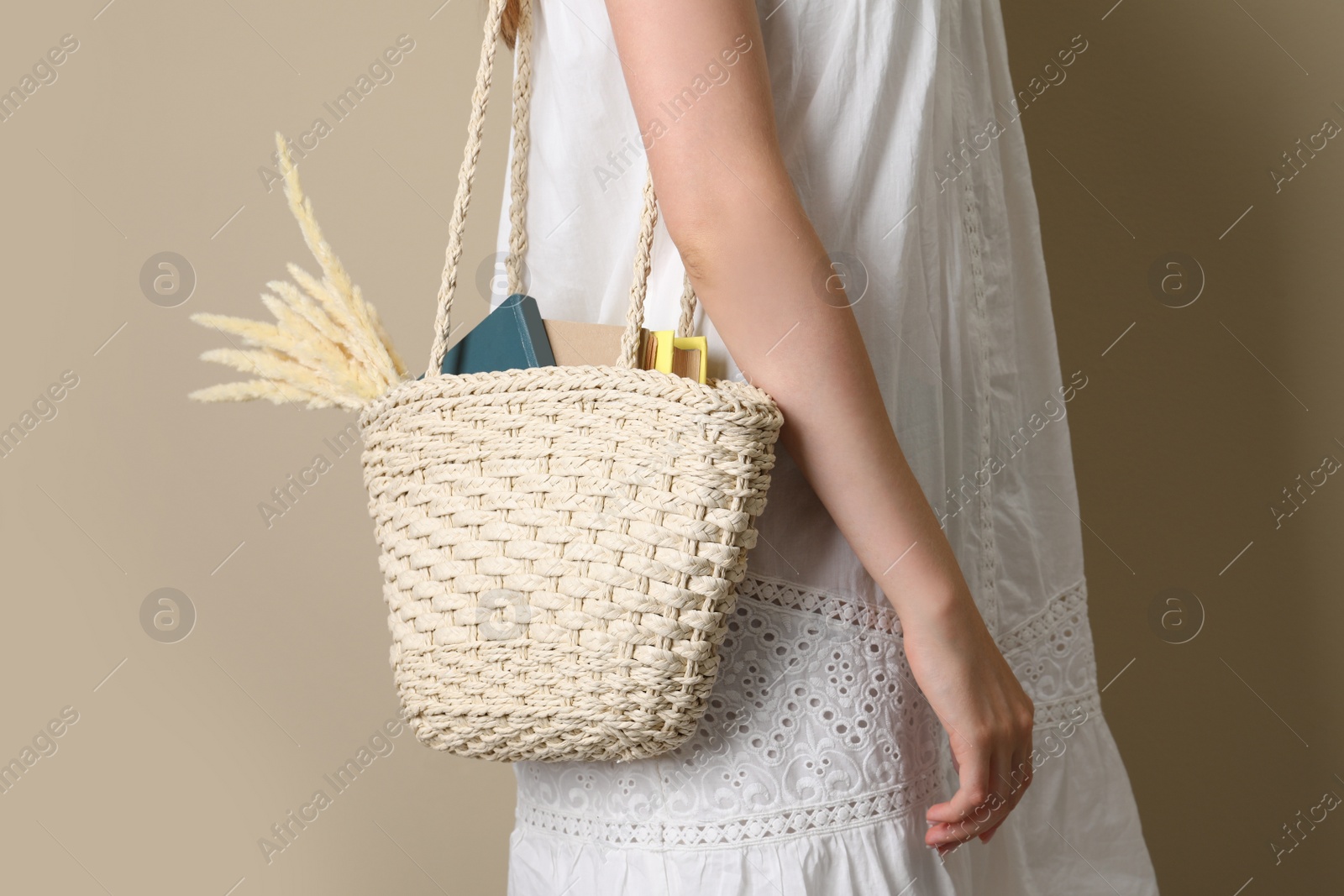 Photo of Woman holding beach bag on beige background, closeup