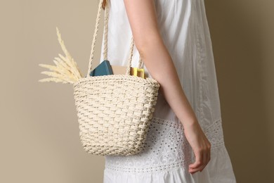 Woman holding beach bag on beige background, closeup