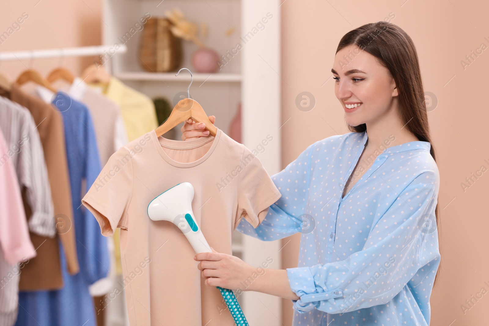 Photo of Woman steaming shirt on hanger at home